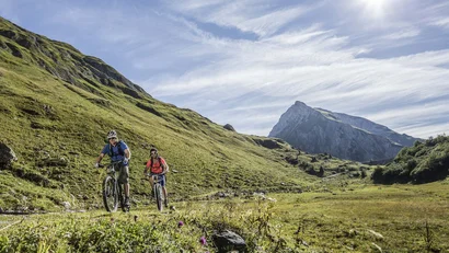 Zwei Radfahrer fahren auf einem Bergweg im sonnigen Tal