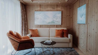 Gemütliche Sitzecke mit weißem Sofa, braunem Sessel und Holzwänden