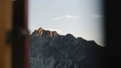 Bergspitze bei Sonnenuntergang durch Fensterrahmen gesehen