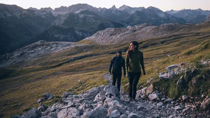 Zwei Wanderer auf einem felsigen Bergpfad in den Alpen bei Dämmerung