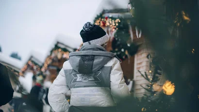 Person in Winterjacke und Mütze auf einem Weihnachtsmarkt